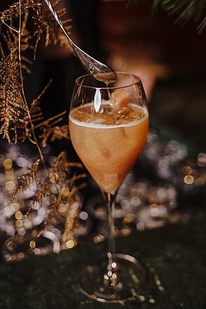Festive cocktail in a wine glass with ice and foam, garnished and stirred with a spoon